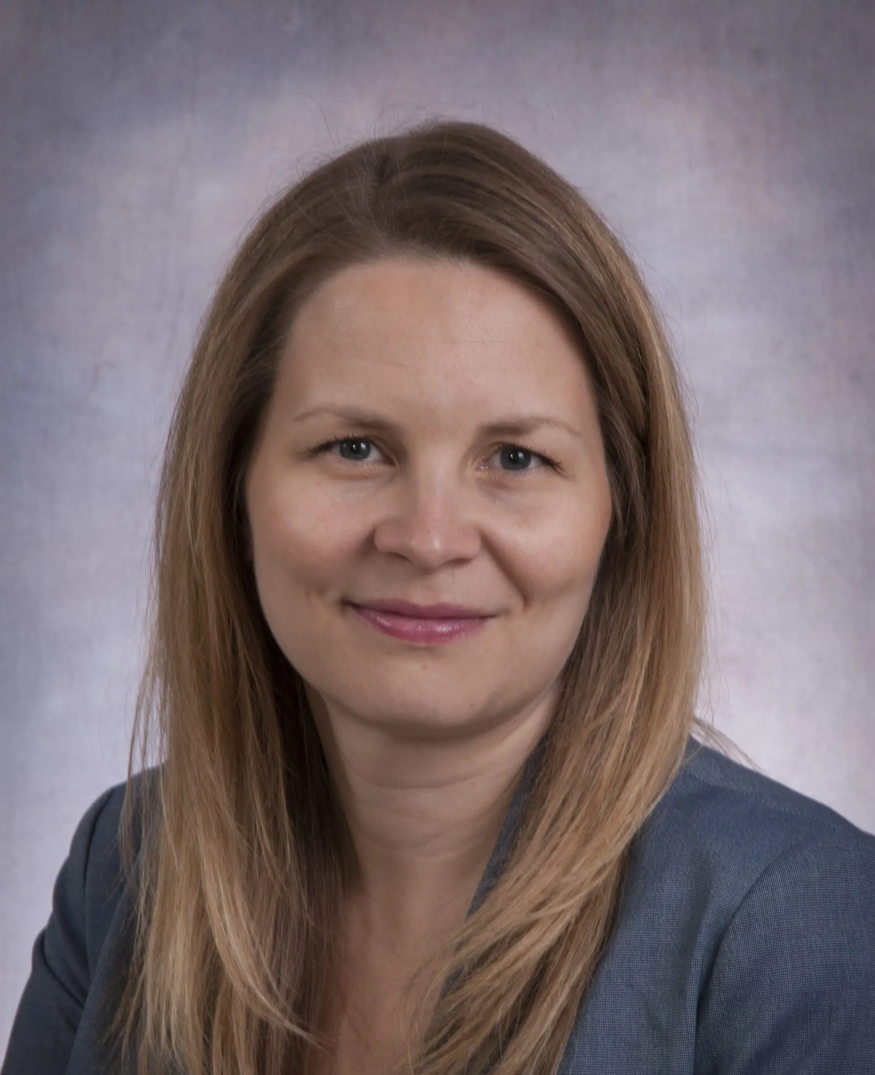 Sara Ahola Kohut smiles against a gray background