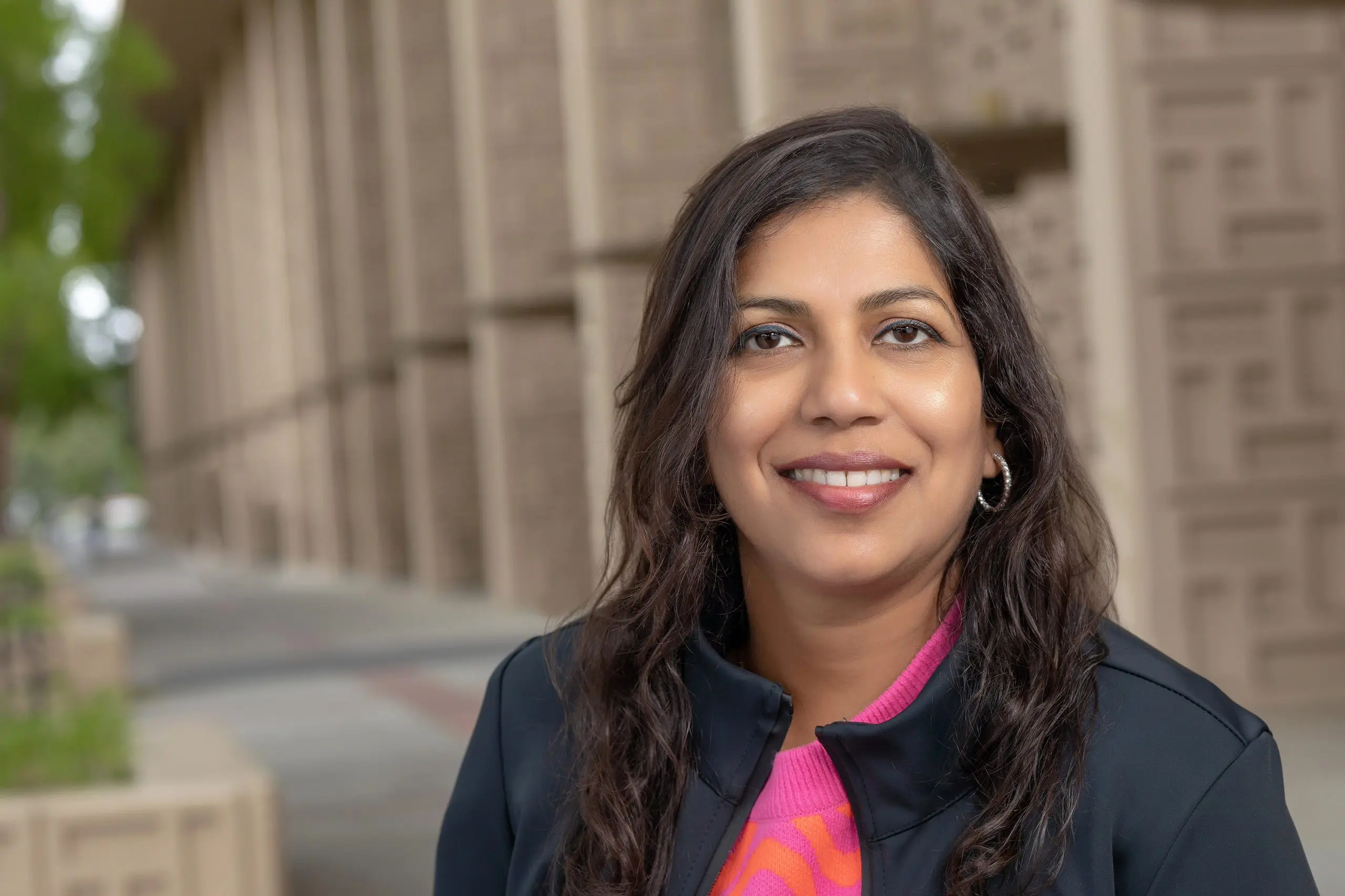 Genevieve D'Souza smiles outside a large building