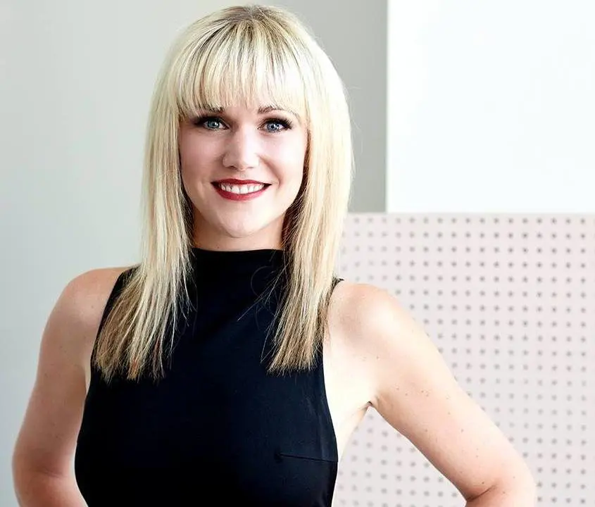 Melanie Noel stands with hands on hips in a black tank top