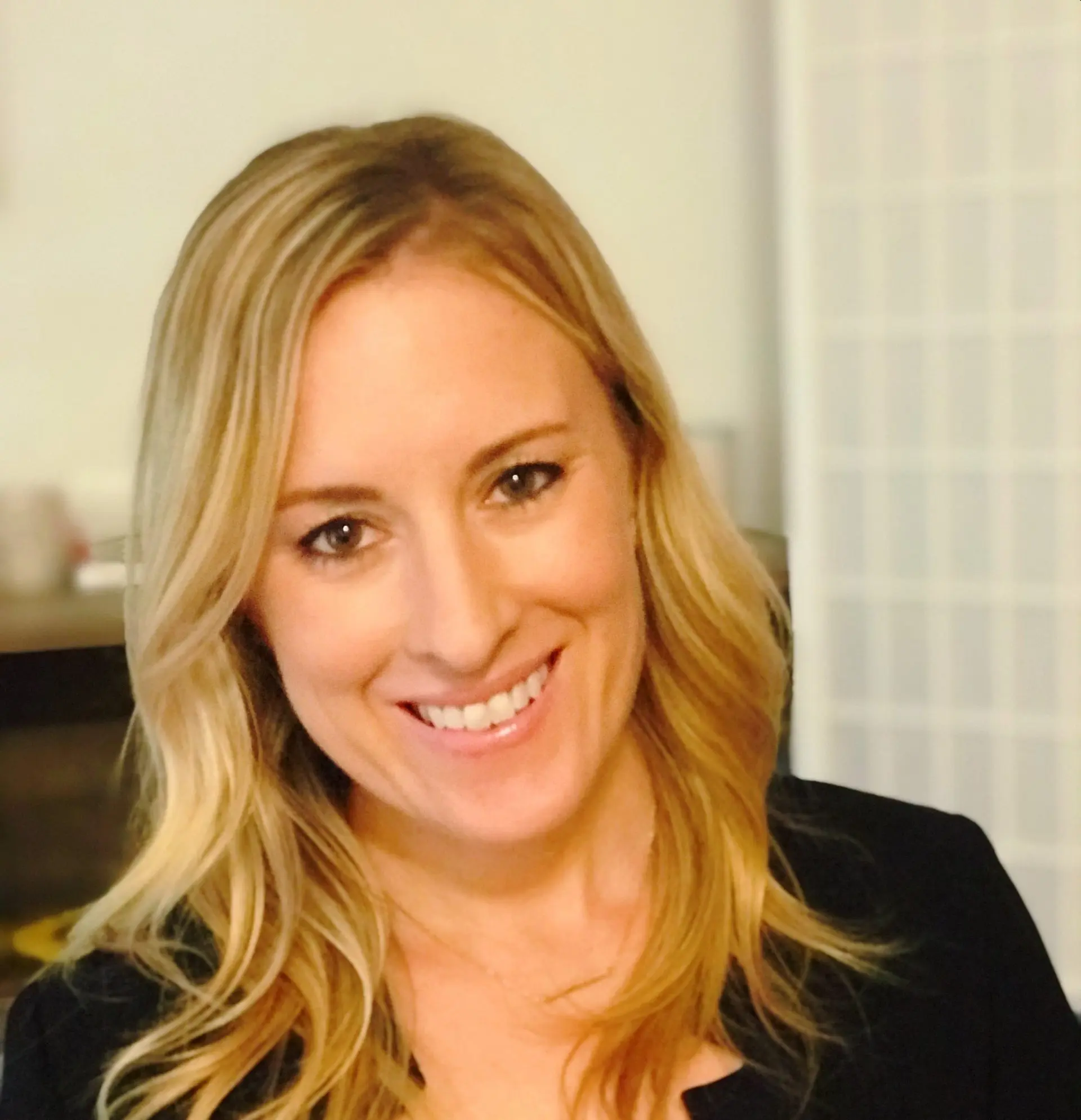 Sarah Martin smiles in a red shirt and black blazer