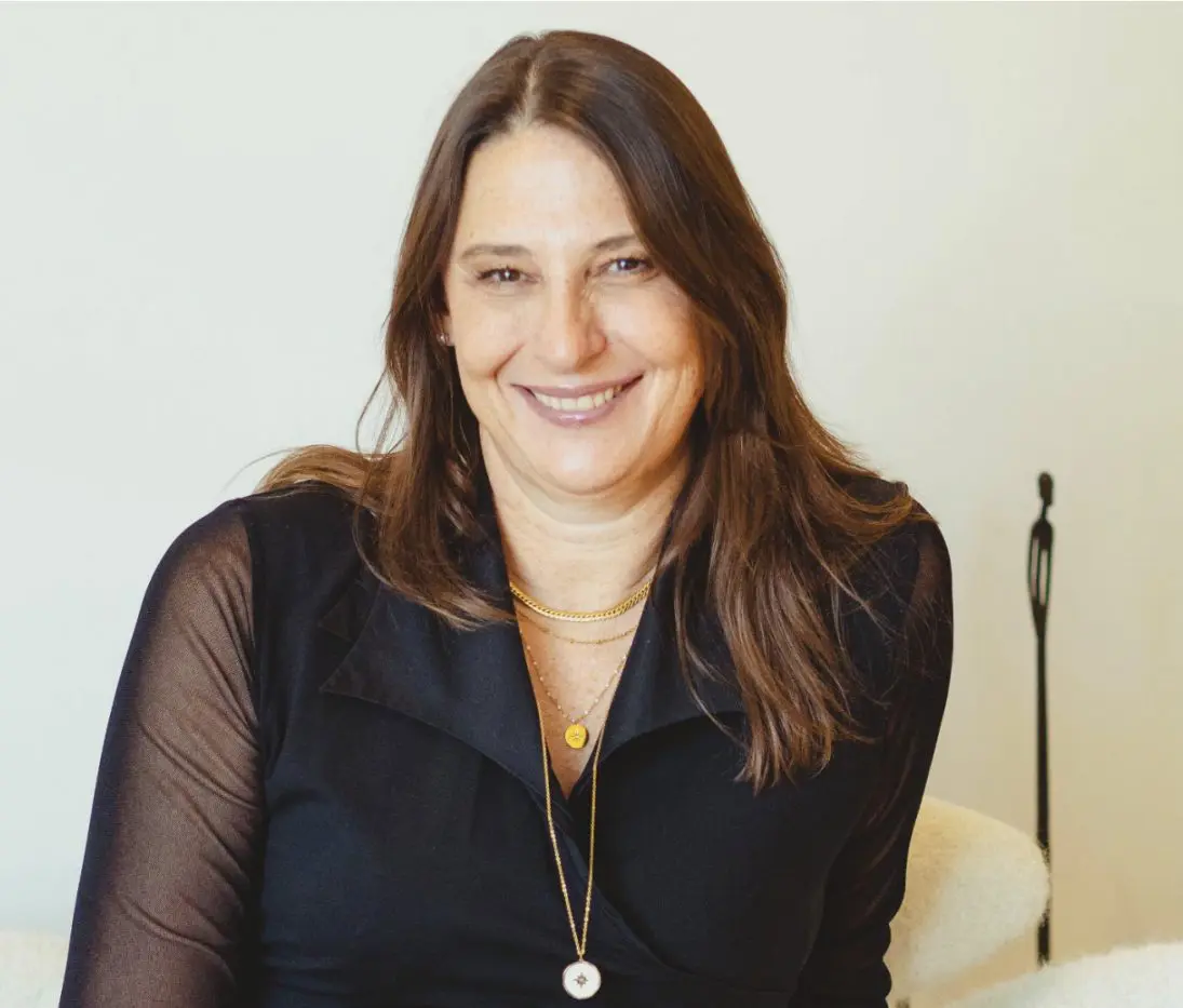 Sabine Combrie smiles in a black top with gold necklaces
