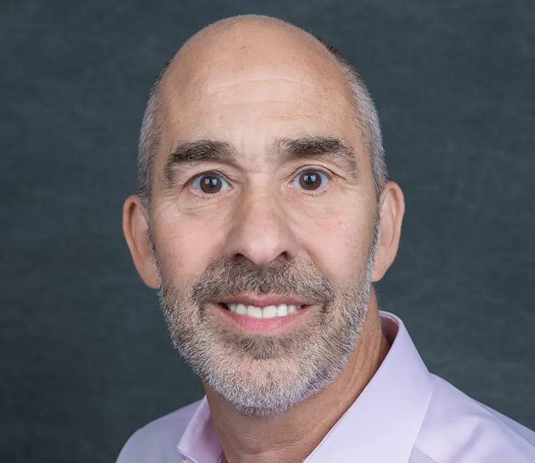 William Zempsky in a pink shirt against a gray background