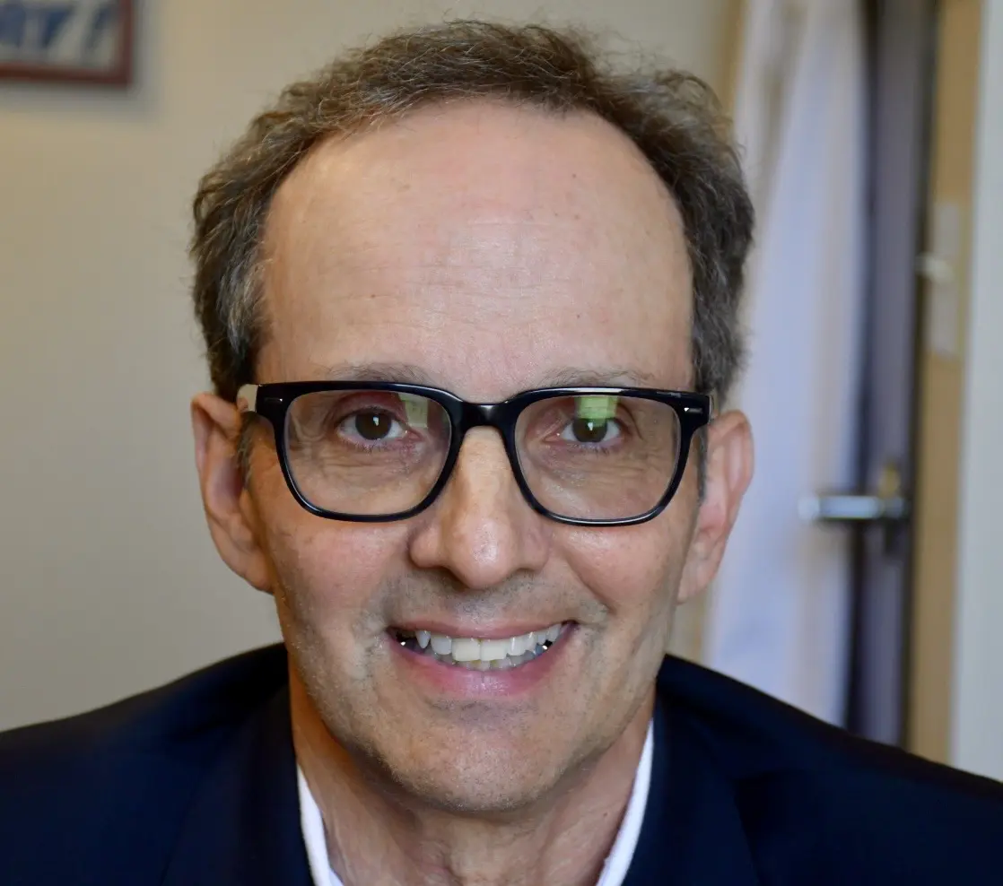 White man with glasses and dark hair smiles