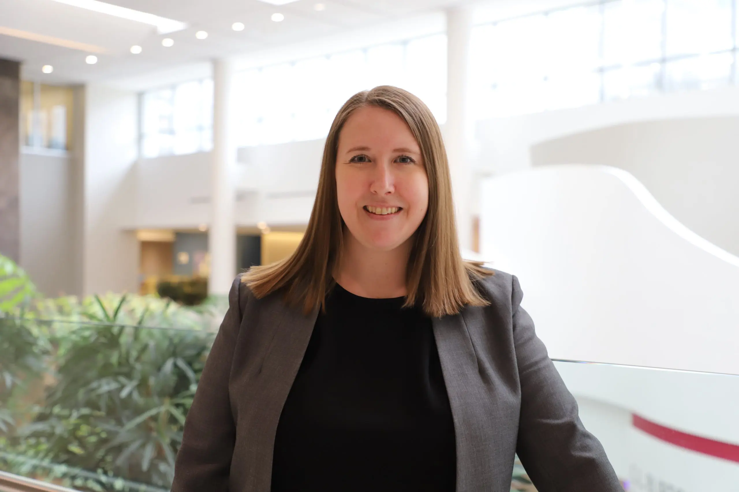 Woman smiles while wearing a black shirt and gray blazer
