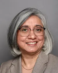 Woman wearing glasses smiles with a gray background