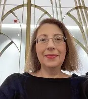 A woman with thin glasses and short hair smiles