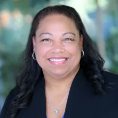 Anya Griffin smiles with a blurred greenery backdrop